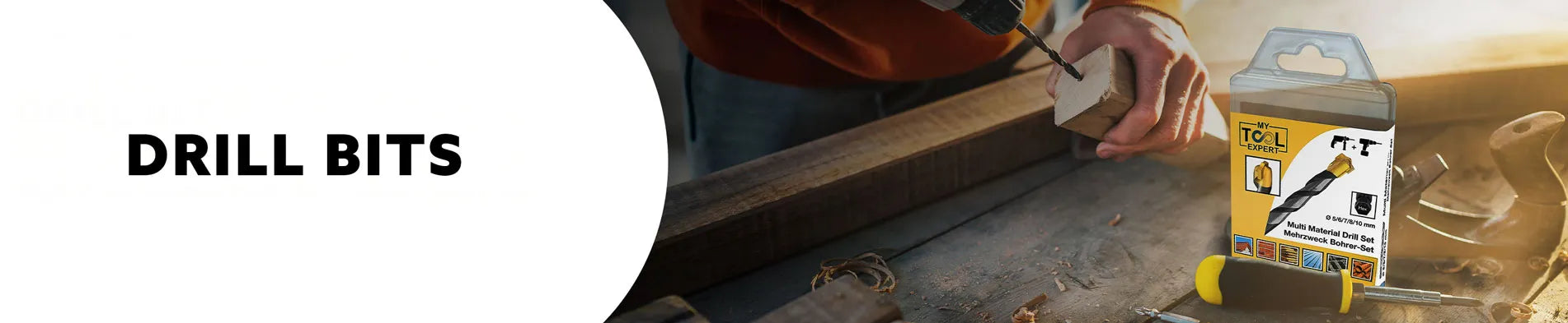 Person using masonary drill bit with a box of drill bits on a workbench.